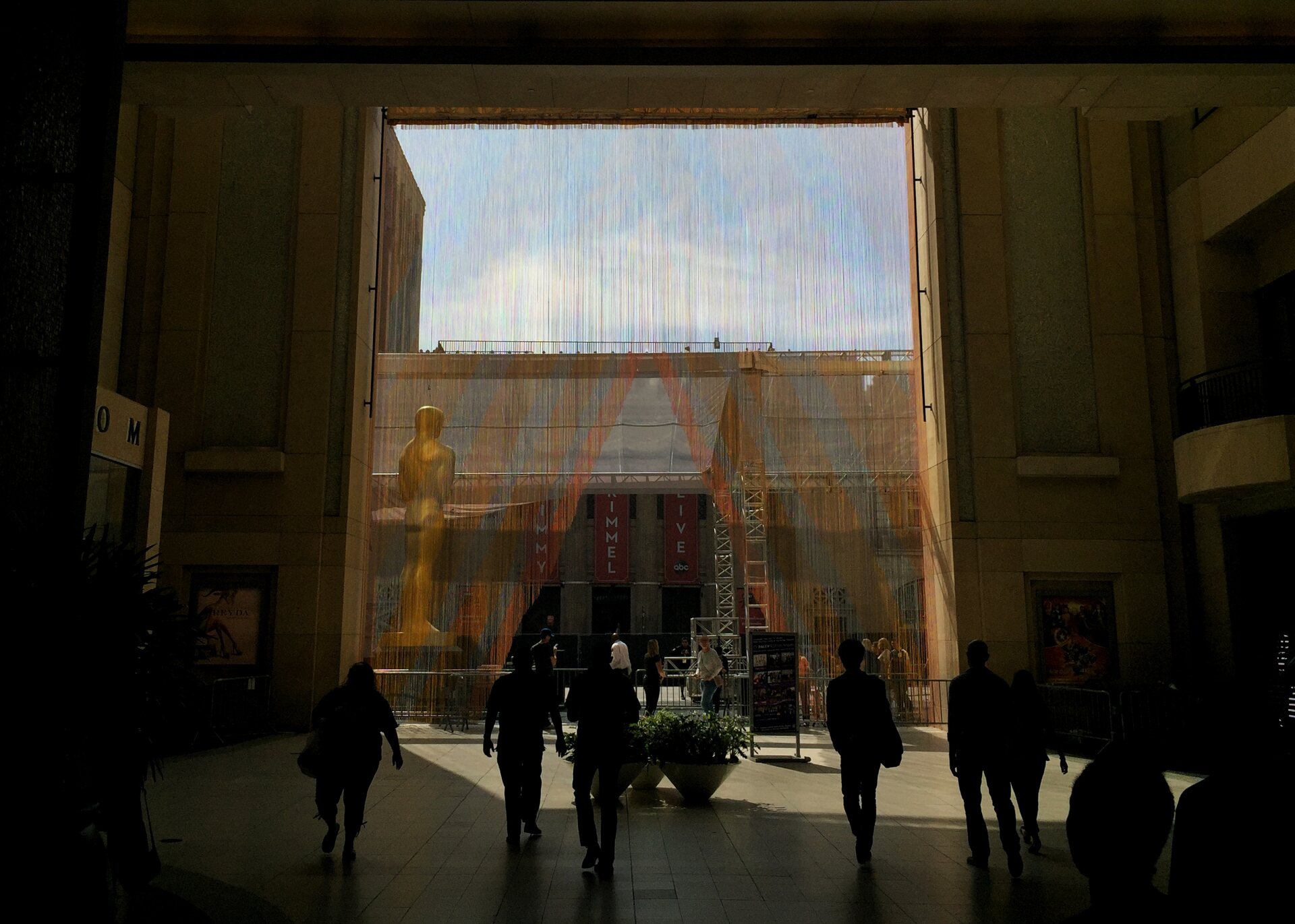 People cross the shadowed entrance of the Dolby Theatre while Academy Awards installations are dismantled after the 2016 ceremony.
