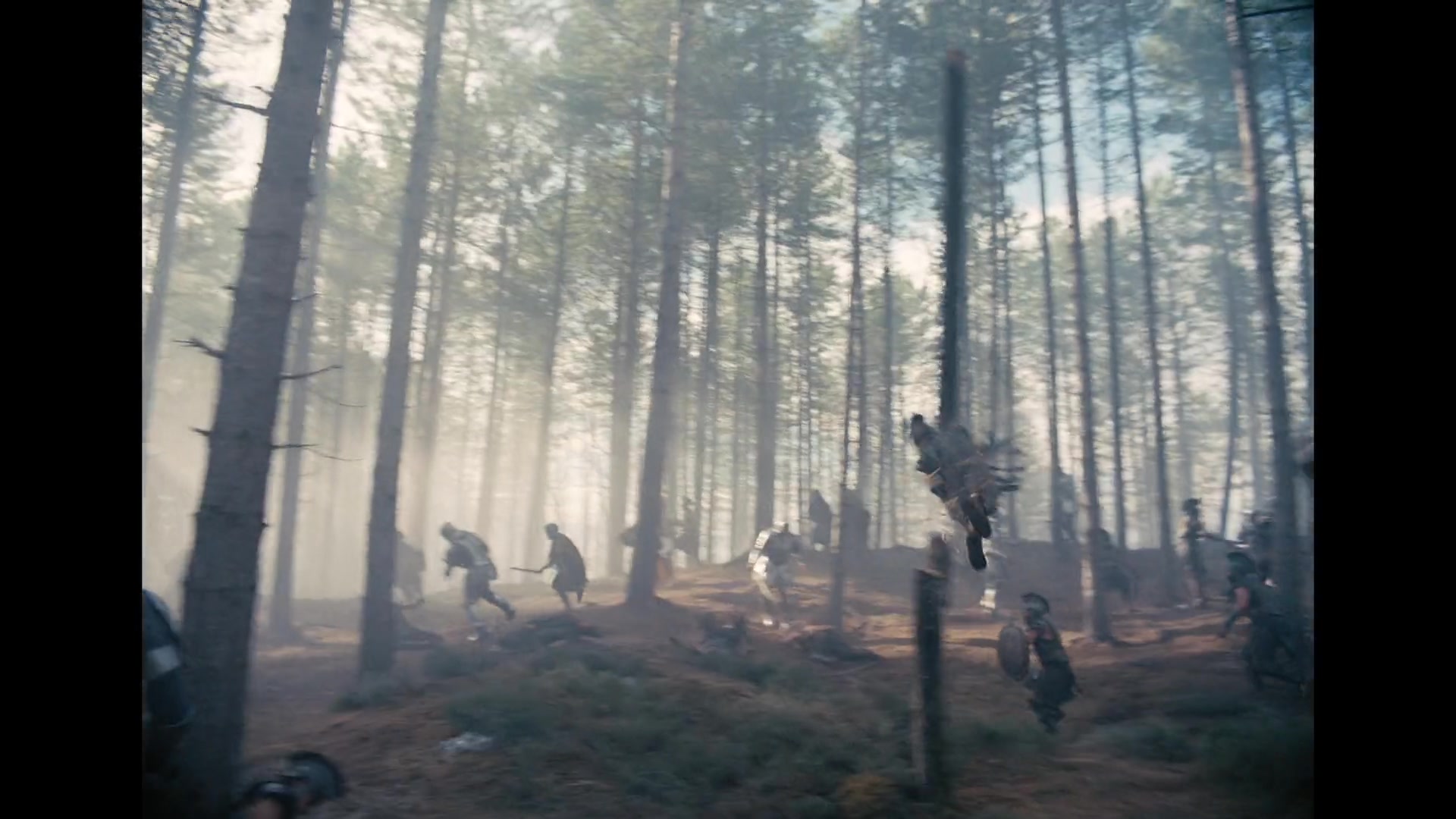 A fighter is thrown through the air while armoured combat continues across a smoke-filled forest in the official trailer for The Odyssey.