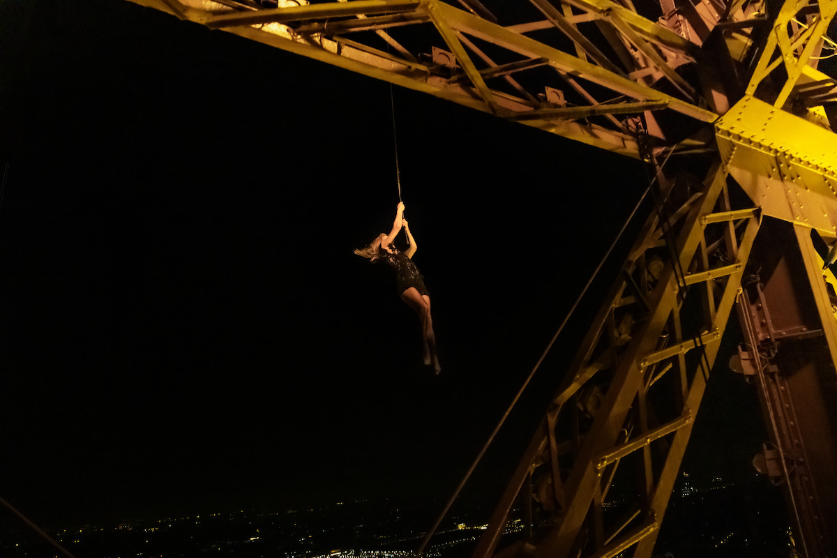 Stunt performer Kelly Phelan hangs outside the Eiffel Tower during production of Murder Mystery 2.