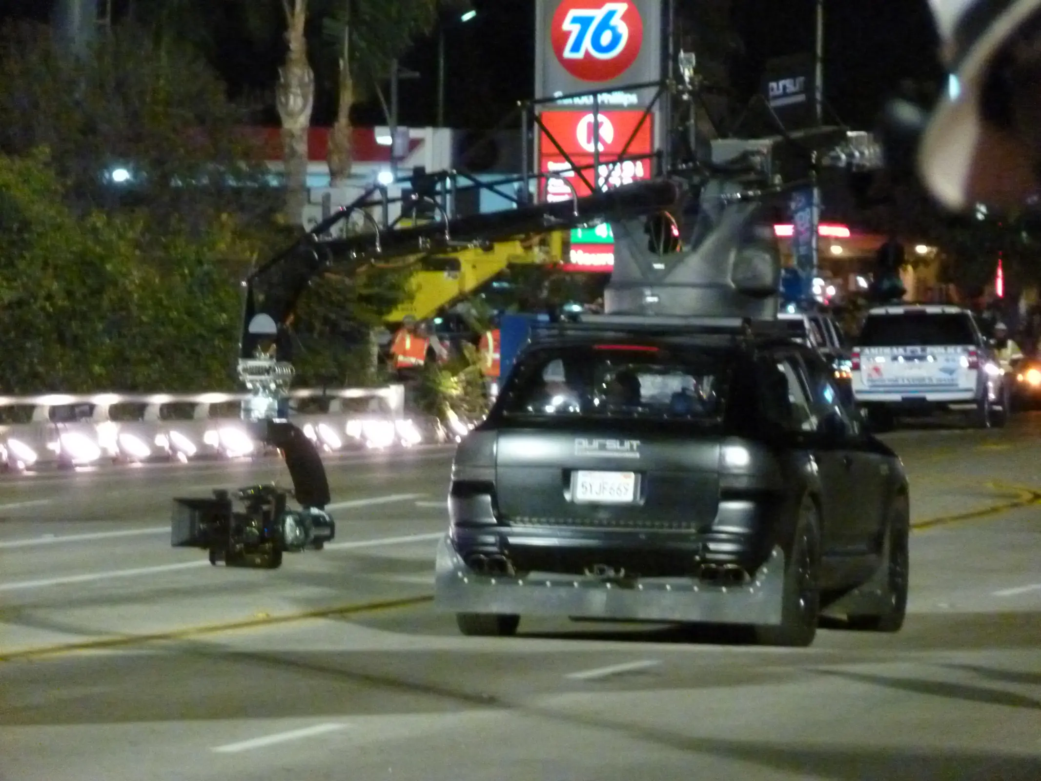 A camera car with a roof-mounted crane arm follows a picture vehicle during a night commercial shoot.