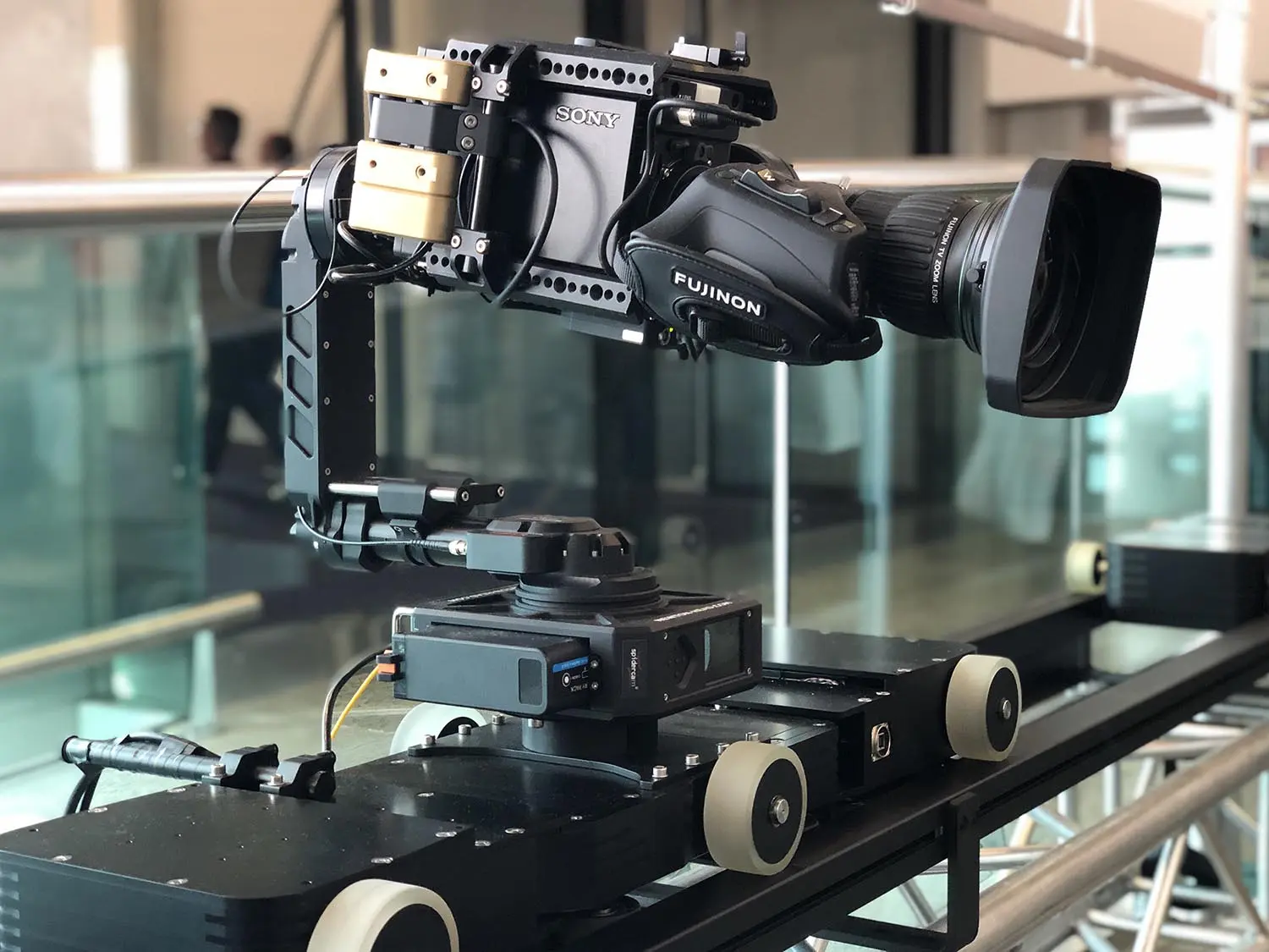A Newton stabilized remote camera head carrying a cinema camera and zoom lens on a powered rail dolly.