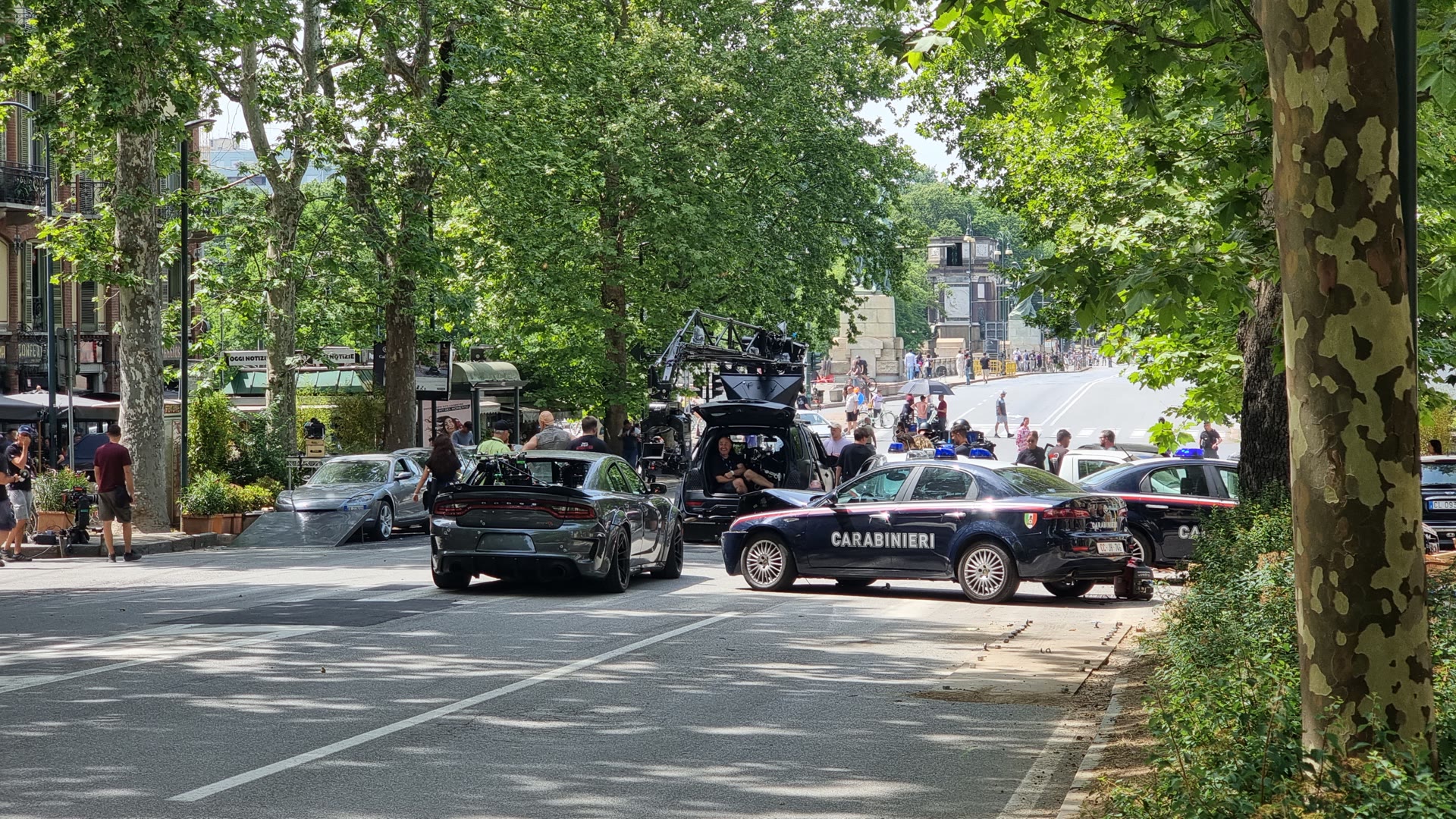 Weites Fast-X-Straßenset in Rom mit Kamerafahrzeug, Crew, Actionfahrzeug und Carabinieri-Fahrzeugen.