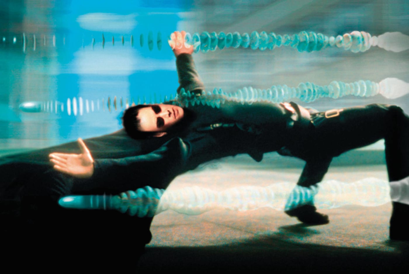 Neo bends almost horizontally backward as multiple bullet trails pass above him during the rooftop bullet-time sequence in The Matrix.