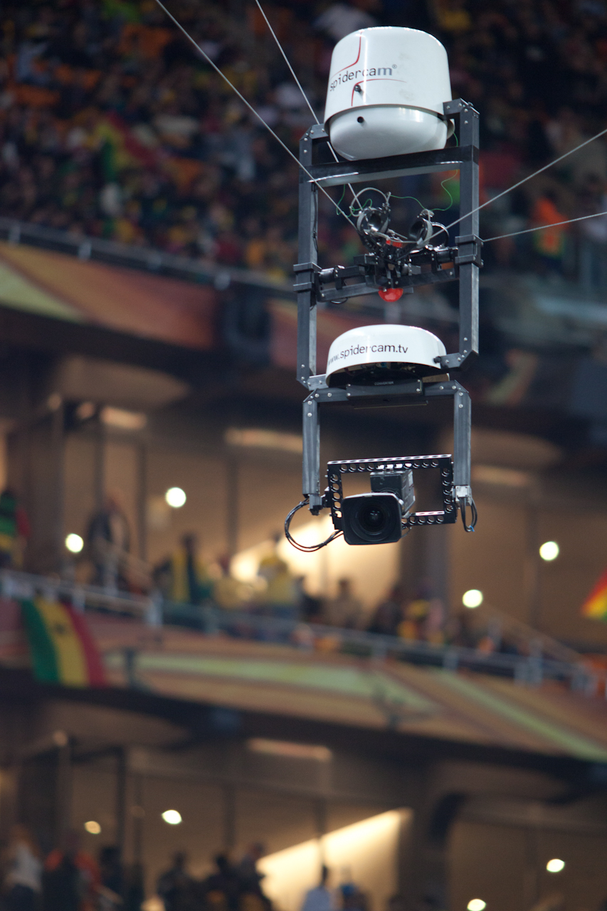 A Spidercam camera carrier hangs from tensioned lines above a stadium during the 2010 football World Cup.