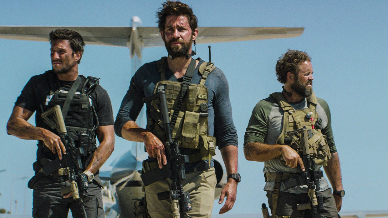 Pablo Schreiber, John Krasinski and David Denman walk in a loose line with rifles in front of an aircraft in 13 Hours: The Secret Soldiers of Benghazi.