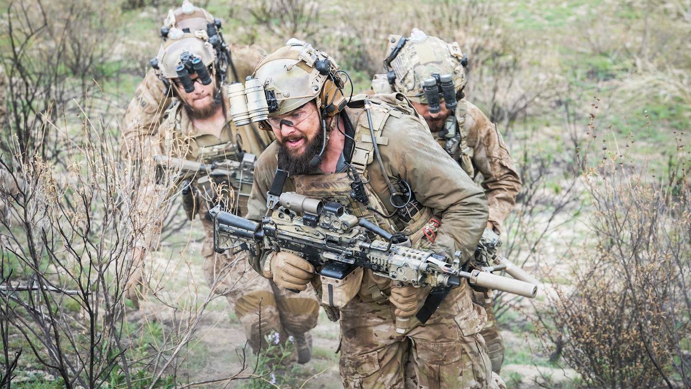 David Boreanaz, Neil Brown Jr. and Max Thieriot move uphill in close formation through scrub in SEAL Team.