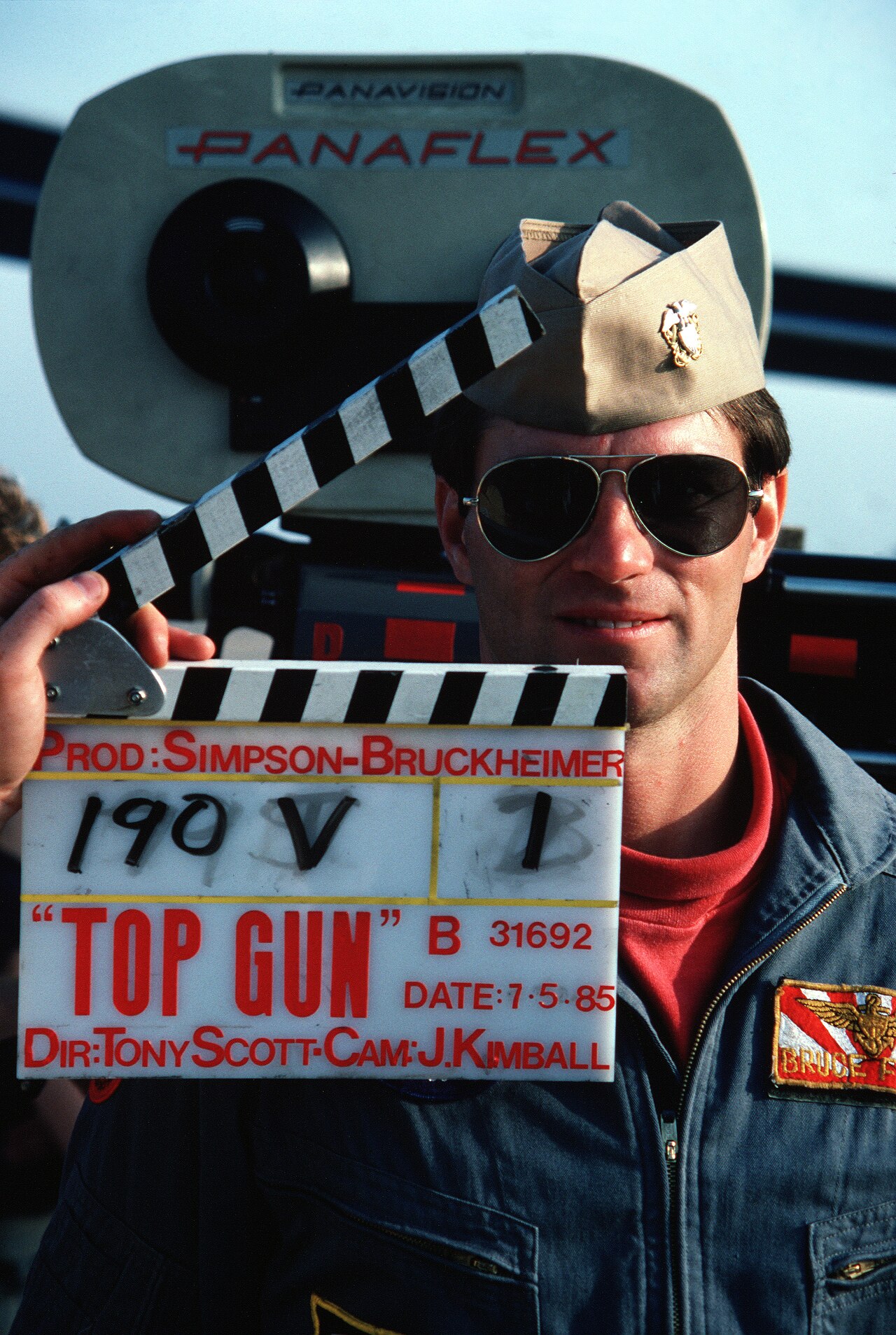 Ein U.S.-Navy-Pilot in Flugausrüstung hält 1985 eine Top-Gun-Filmklappe vor einer Panaflex-Kamera.
